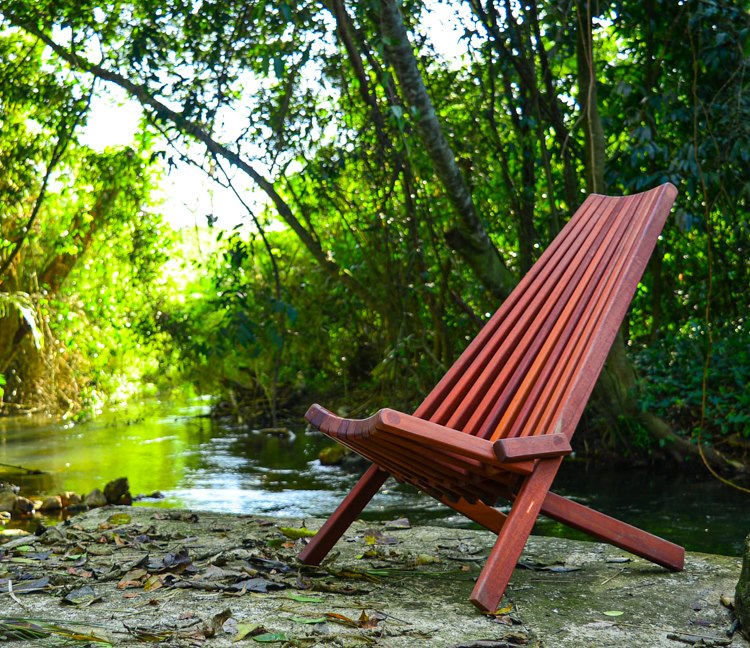 A beautiful hand-made wooden clam chair next to a river